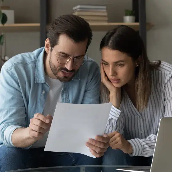 Un couple examine les documents relatifs à un prêt pour mauvais crédit, semblant préoccupé et engagé dans la discussion.