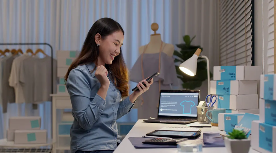 A woman sitting at a desk, using her phone.
