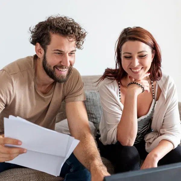 A man and a woman sitting on a couch, discussing an emergency loan option with no refusal.