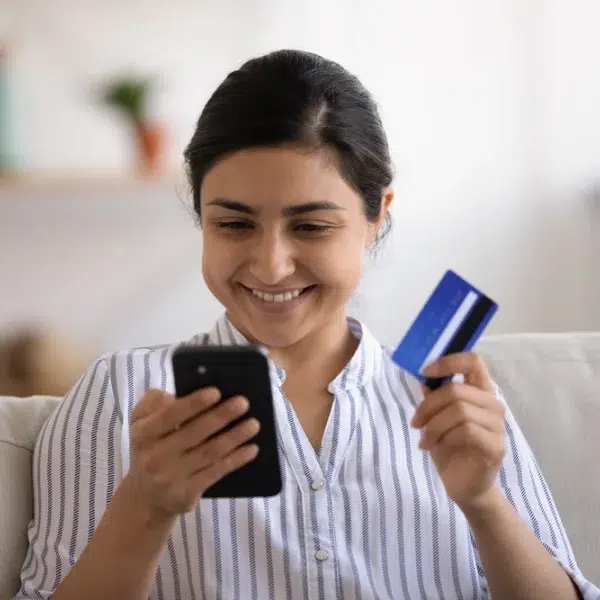 A woman using her smartphone to make a payment for a purchase, highlighting the convenience of instant loans.