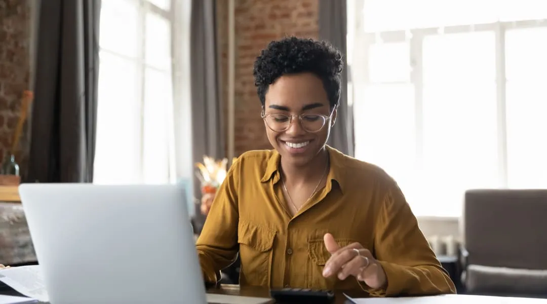 A woman happily using her laptop computer, applying for a loan without a credit check.