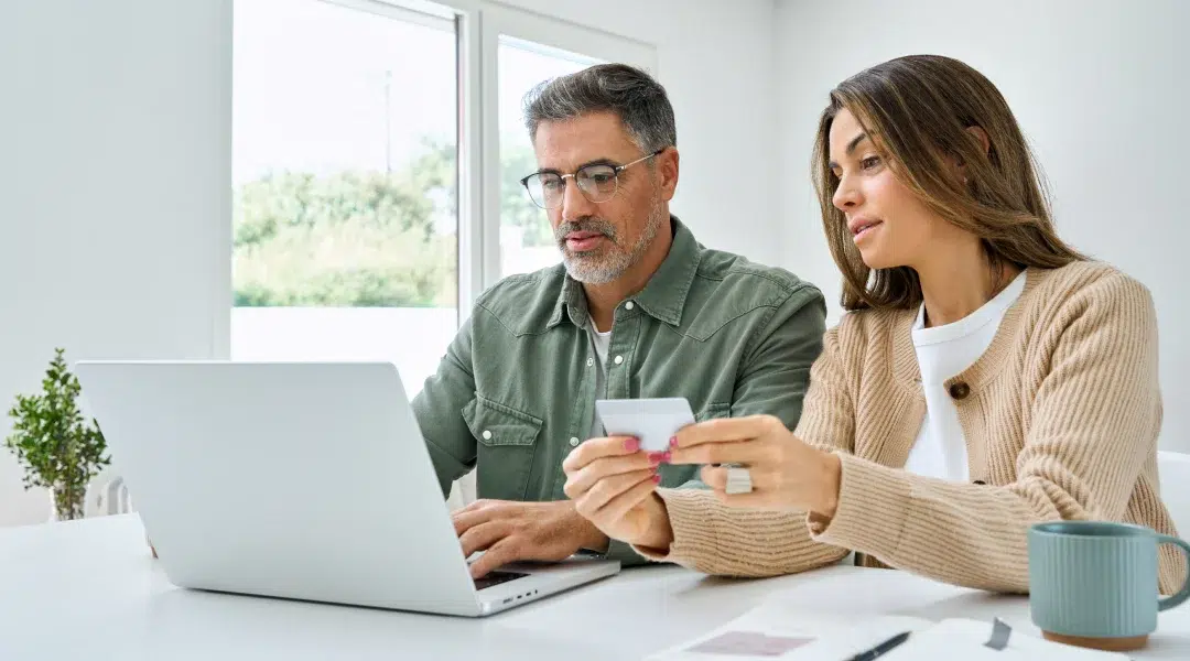 A man and woman examine a laptop, credit card in hand, discussing options for a personal loan.