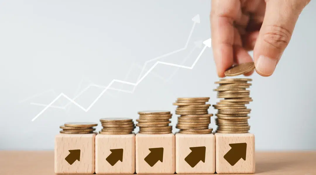 A hand placing coins on wooden blocks, illustrating growth in credit score with an upward arrow and graph.