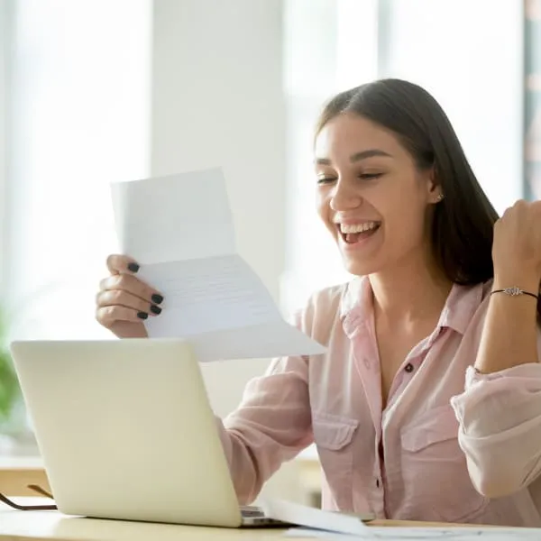 Woman happily holds paper, suggesting loan without credit check.