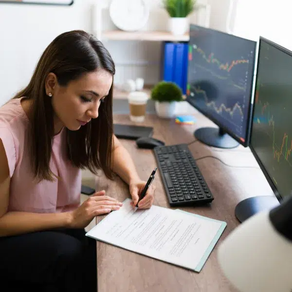 A woman sits at a desk, writing on paper, with a focus on instant financing options.