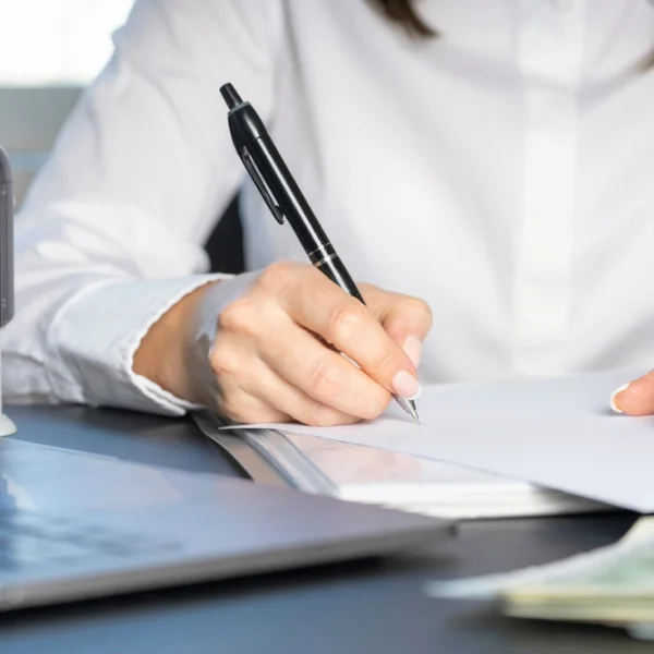A woman writes on paper with a pen, possibly drafting a request for instant loans.