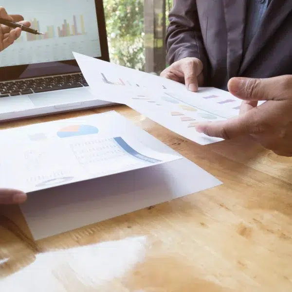 Two individuals analyze graphs on a laptop, discussing data related to a secured personal loan.