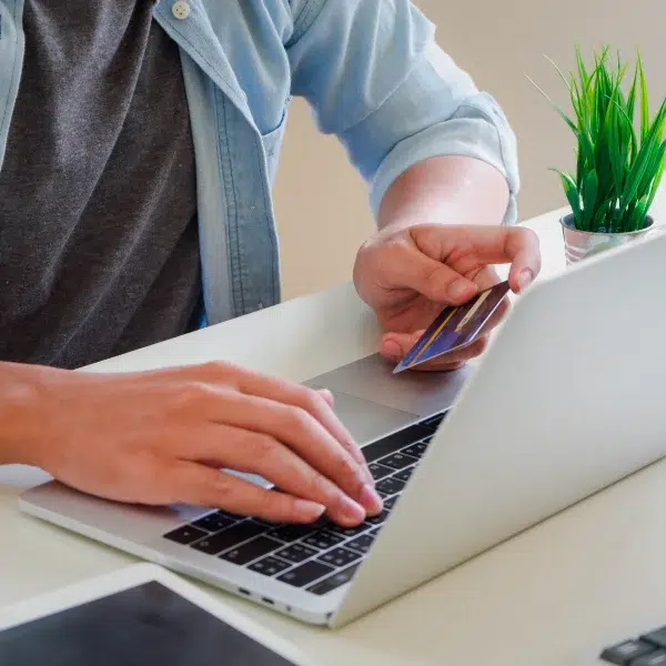Un homme utilise un ordinateur portable et une carte de crédit pour effectuer un achat en ligne.