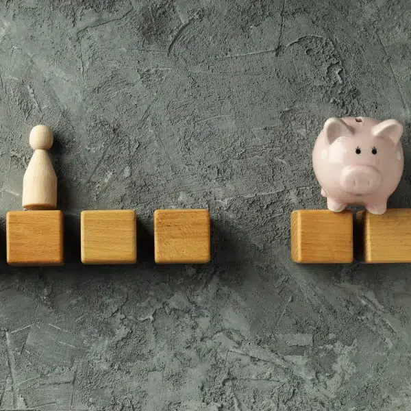 Tirelire en forme de cochon et blocs en bois sur un mur en béton, symbolisant l'épargne et les prêts personnels.