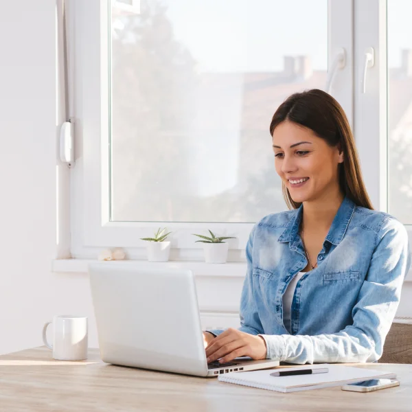 Une femme assise à une table, utilisant un ordinateur portable, dans un environnement accueillant pour les personnes à faible revenu.