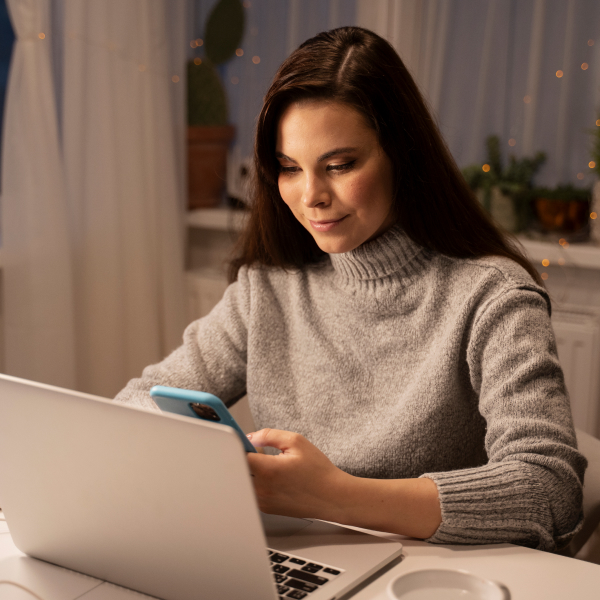 Femme utilisant un ordinateur portable et un téléphone tout en envisageant un prêt personnalisé avec Alter Cash