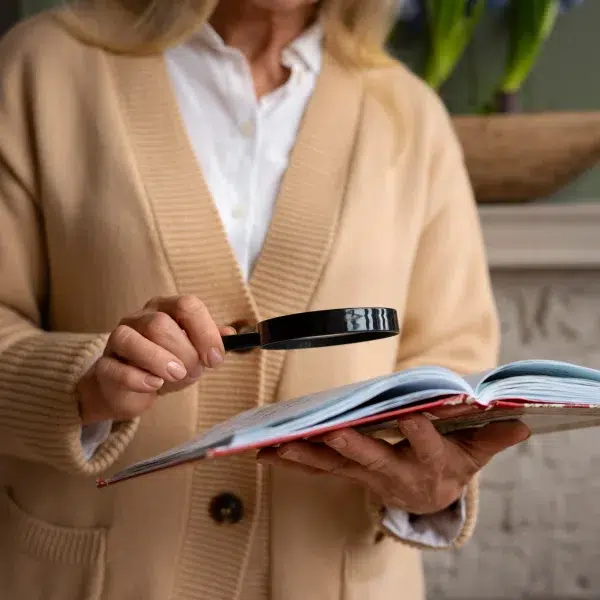 Une femme tenant une loupe, examinant attentivement un document.