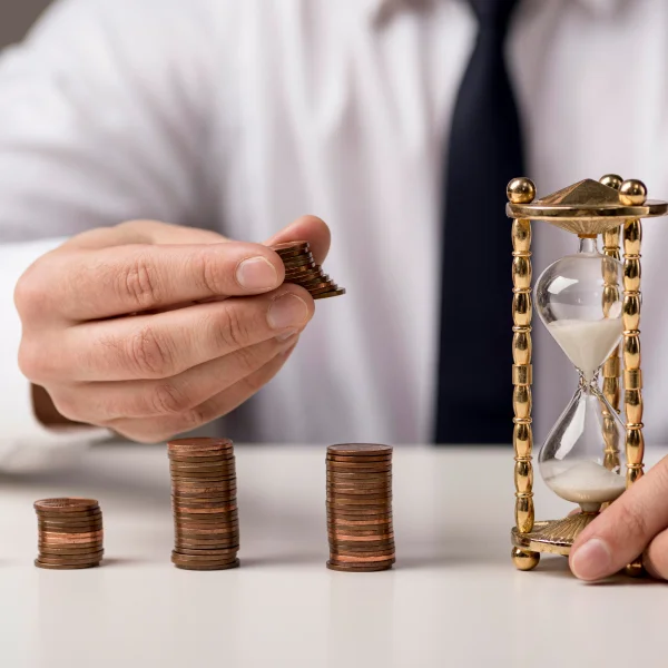Un homme tient une pièce de monnaie et un sablier, symbolisant le temps et l'argent dans un contexte de prêts personnels.