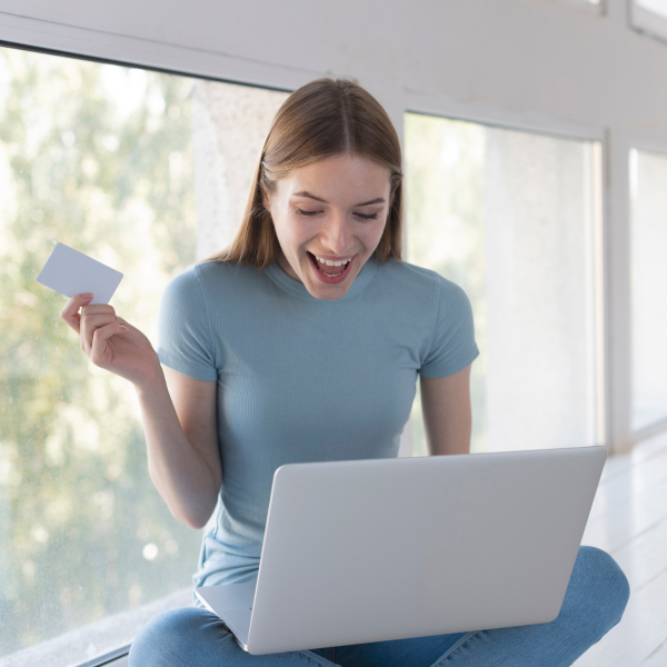 Femme heureuse tenant une carte de crédit tout en effectuant une procédure simplifiée de demande de prêt en ligne.